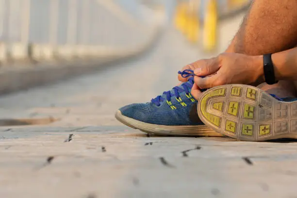 Photo of Man hand tying sport shoe laces in casual clothes after workout.
Young fitness man running outside city. People fitness, exercise, workout and healthy lifestyle concept.