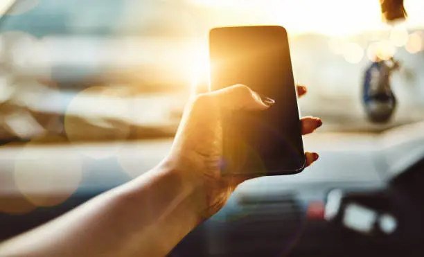 Cropped shot of an unrecognizable woman using her smartphone while driving