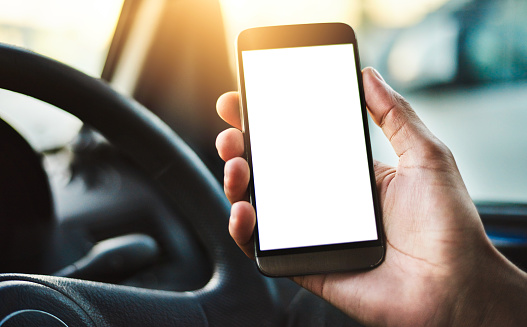 Cropped shot of an unrecognizable woman holding up her smartphone while driving