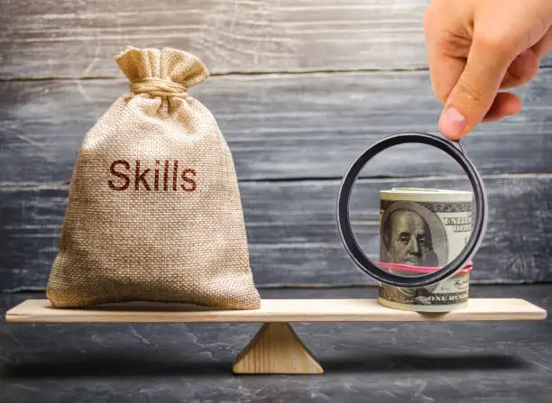 Photo of The concept of decent wages of an employee for useful skills. Professionals of the business. Low-quality incompetent courses private for teaching another popular profession for money. Balance. Scales