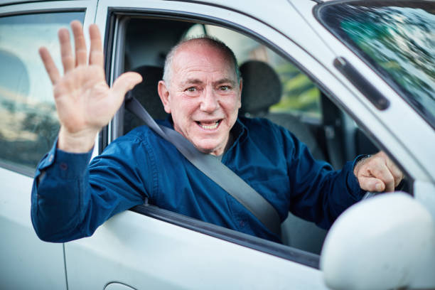 istock Senior man driviing car waves in greeting 1148801524