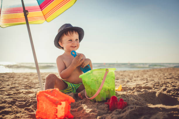 Cute child sitting on the beach and building a sand castle Cute happy boy on beach vocations near the sea pinus pinea photos stock pictures, royalty-free photos & images