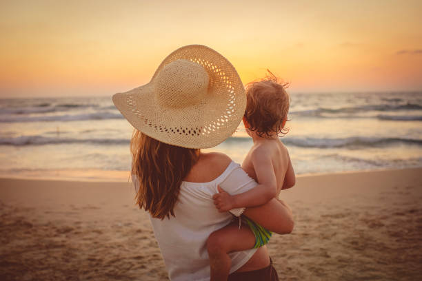 istock Mother with son enjoying sunset on the beach 1148804201