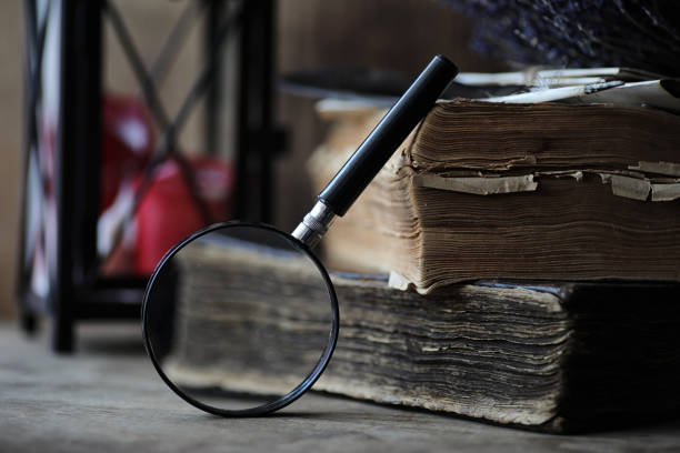 Old books on a wooden table and glass magnifier