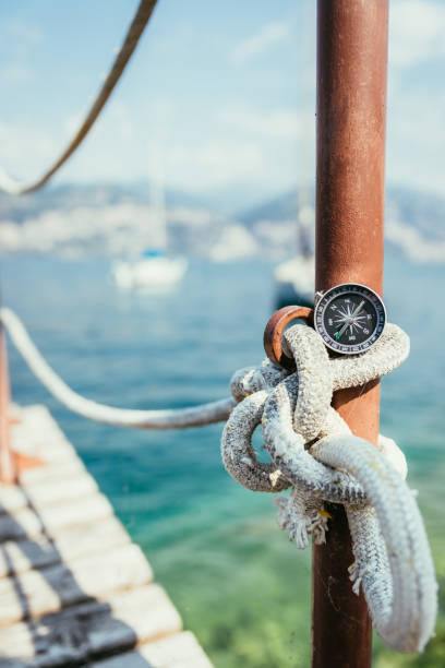 istock Sailing: nautical compass on a sailing rope, pier. Sailing boats in the background. 1148807132