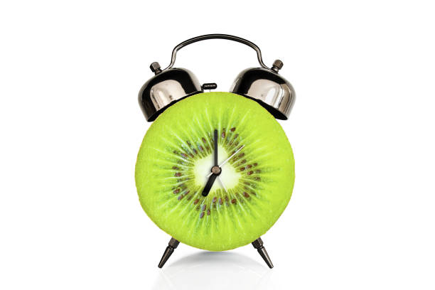 istock Kiwi slice on alarm clock, isolated on white background, fruit and vitamins diet at breakfast nutrition concept 1148807329