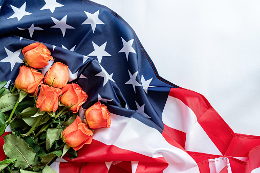 Independence Day USA concept. Memorial Day. Roses on the US flag flat lay top view