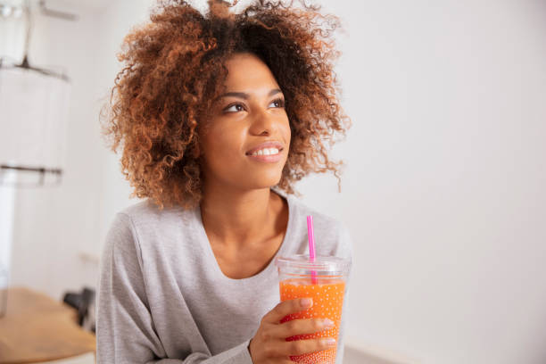 istock Happy mixed race woman holding smoothie, looking to camera. 1148808848