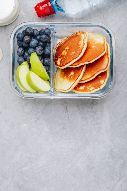 istock Meal prep containers with pancakes, blueberry and apple. Breakfast in lunch box. Top view. 1148812172