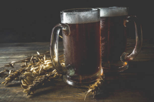 Two Homemade craft beer mugs, dark wooden background copy space