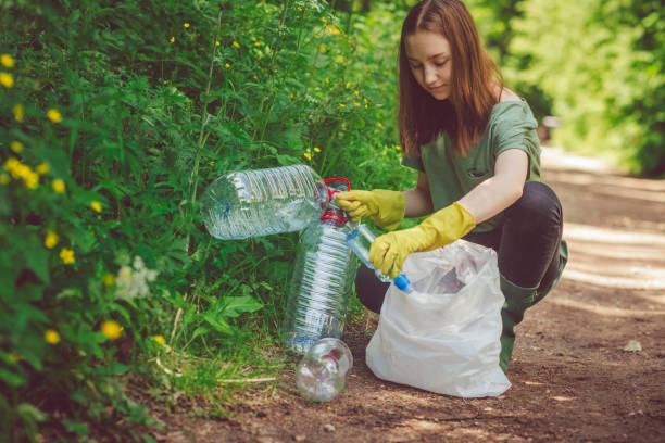 a menina voluntária recolhe o lixo-frascos plásticos na mola ou no verão ao ar livre - mulher catando lixo - fotografias e filmes do acervo