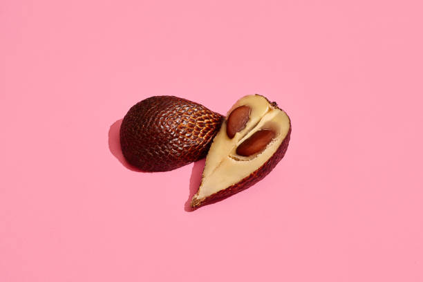 Close up high quality image of cutted salacca halves, fruit composition on coral pink background. Mockup, flat style