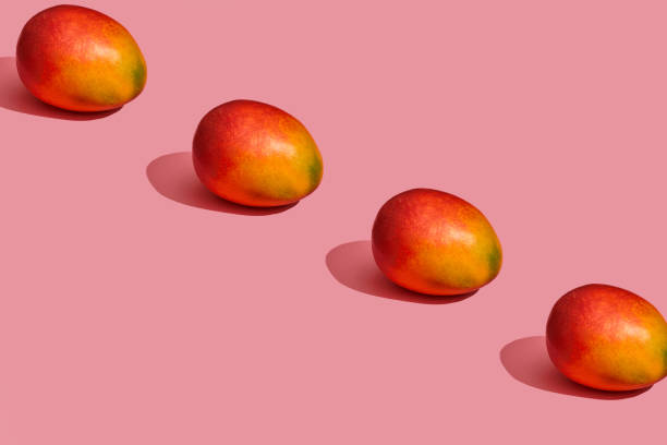 istock Pattern composition of a sweet tasty mango lying next to a pink background , top view 1148815994