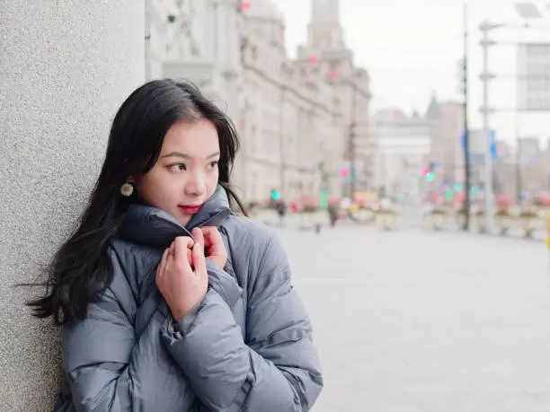 Street photography of beautiful young brunette woman in sunny winter city. Outdoor fashion portrait of glamour young Chinese stylish lady. Emotions, people, beauty and lifestyle concept.