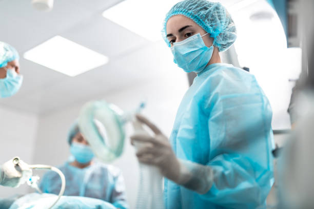 Medical worker looking at oxygen mask while standing in operation room stock photo