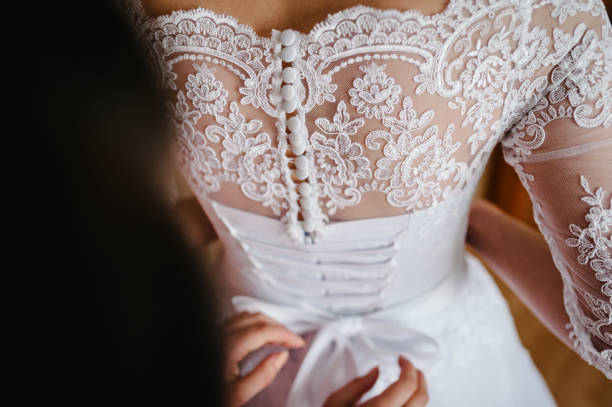 mutter hilft braut fasten korsett in der nähe in hochzeitskleid und bekommen ihr kleid, vorbereitungskonzept am morgen für hochzeitszeremonie. - bride caucasian wedding ceremony close up stock-fotos und bilder