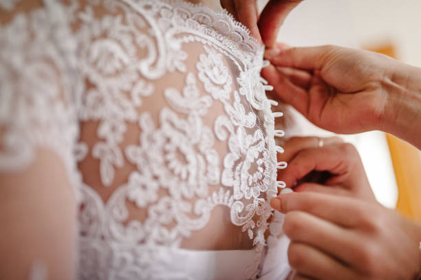 demoiselle d’honneur, mère aidant mariée attacher corset et obtenir sa robe, la préparation de la mariée dans le matin pour le jour du mariage. - wedding dress wedding domestic room bride photos et images de collection