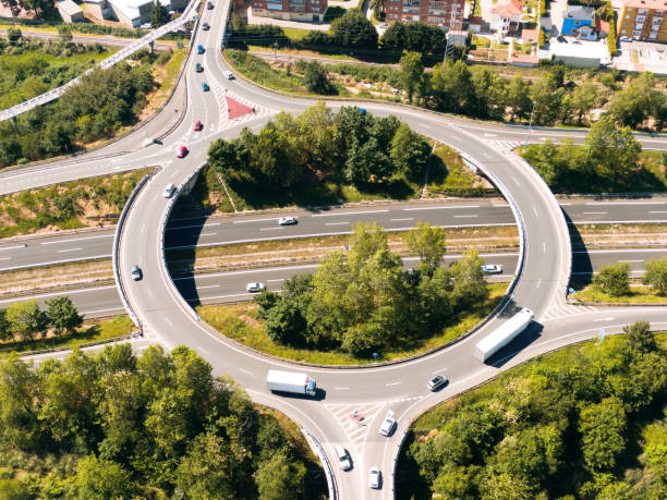 mehrere spurige autobahn mit großem kreisverkehr darüber - driving industry land vehicle multiple lane highway stock-fotos und bilder