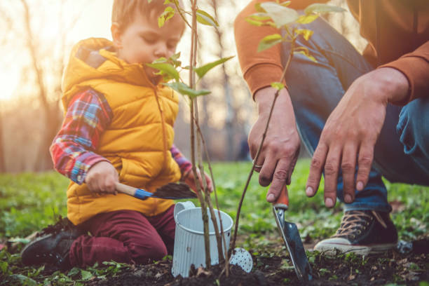 istock Child and father planting tree on Arbor day in springtime 1148819422