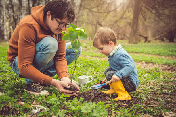 Family planting tree on Arbor day in springtime Little boy and his father gardening in spring Arbor Day stock pictures, royalty-free photos & images