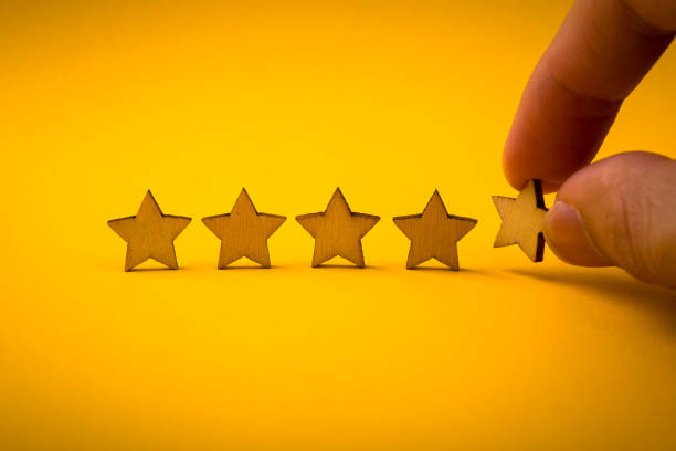 istock Hand putting wooden five star shape on yellow background 1148823599