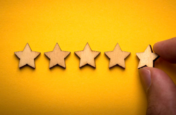 istock Hand putting wooden five star shape on yellow background 1148823603