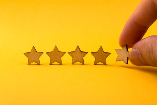 istock Hand putting wooden five star shape on yellow background 1148823605