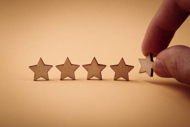istock Hand putting wooden five star shape on yellow background 1148823619