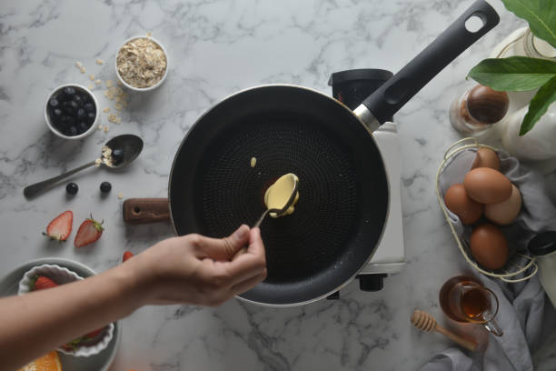 pfannkuchen machen, kuchen, backvoransicht von bäckerhandwerken gießen oder den teig auf die pfanne werfen. konzept der kochzutaten und methode auf weißem marmorgrund, dessert-rezepte und hausgemacht. - lowcarb stock-fotos und bilder