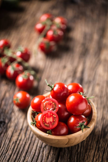 istock Fresh cherry tomatoes in wooden bowl on old oak table 1148824982