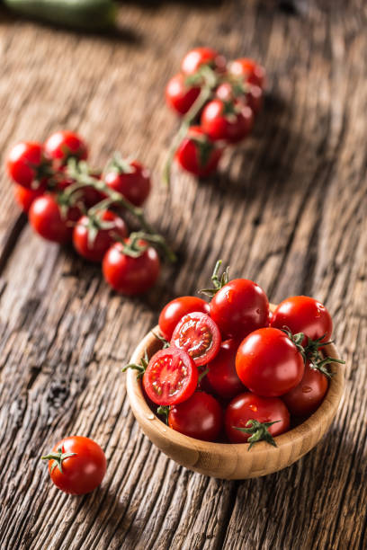 istock Fresh cherry tomatoes in wooden bowl on old oak table 1148824987
