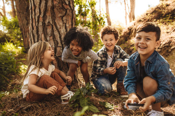 Group of cute kids playing in forest Group of cute kids sitting together in forest and looking at camera. Cute children playing in woods. explorer photos stock pictures, royalty-free photos & images