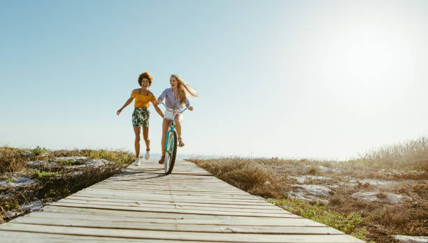 istock Friends with a bicycle on the seaside boardwalk 1148825786