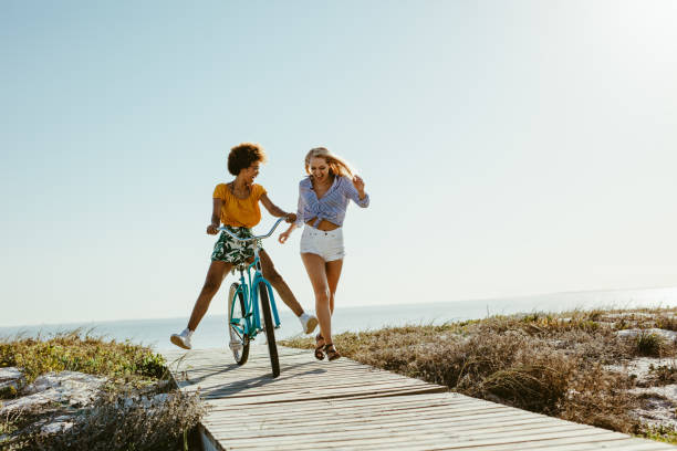 istock Two women having fun with a bicycle at beach 1148825969
