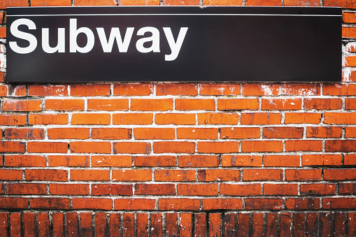 Subway sign of metro access on a red brick wall in New York City