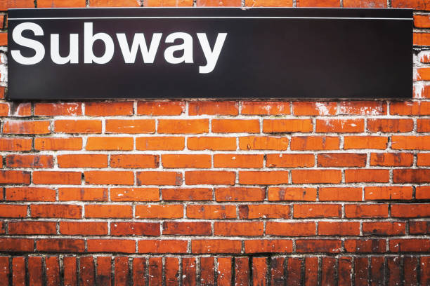 Subway sign of metro access on a red brick wall NYC stock photo