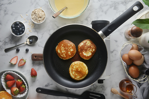 Pancakes onto the pan. Concept of Cooking ingredients and method on white marble background, Dessert recipes and homemade.