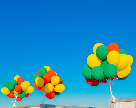 Colourful helium balloons against a blue sky background with copy space