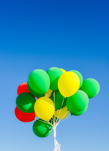Colourful helium balloons against a blue sky background with copy space - vertical