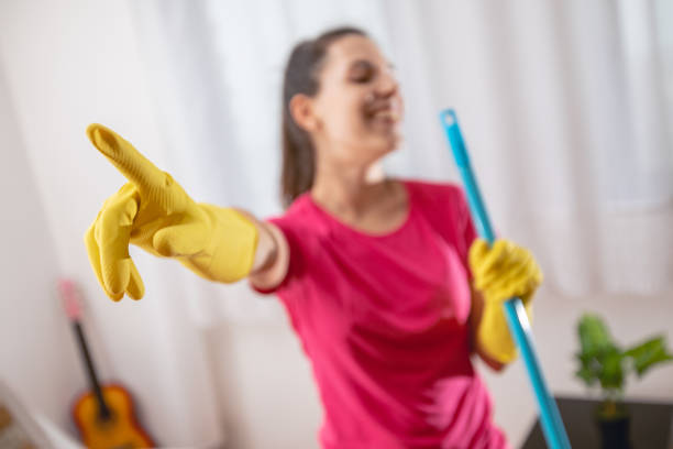 A woman in an apron cleans the floor with a mop in a home kitchen, isolated on a white background