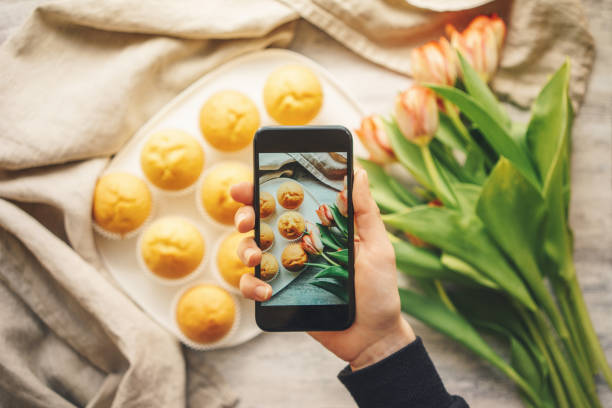 donna che scatta foto di cupcakes con smartphone - muffin blueberry muffin blueberry food foto e immagini stock