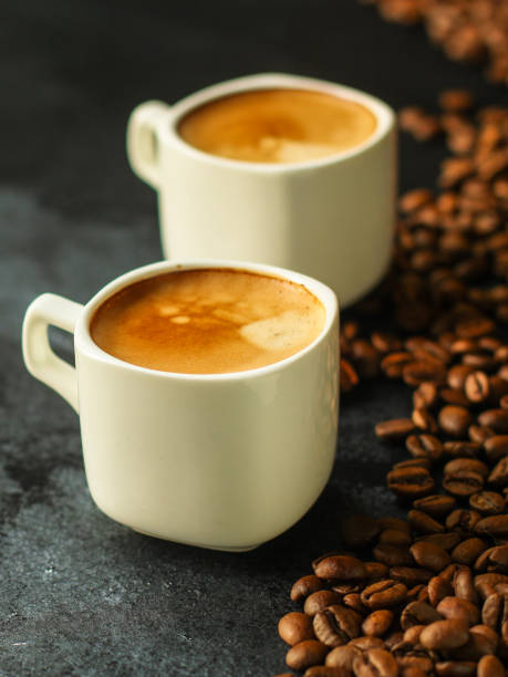 istock coffee in a white cup and coffee grain scattered on the table (freshly brewed hot drink with foam). food background. top 1148834124