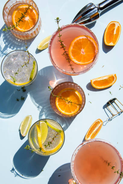 Trendy cocktails on light blue background with lemon and orange slices. stock photo