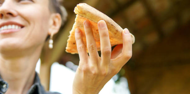 istock Woman eating pizza outdoors in a park 1148836850