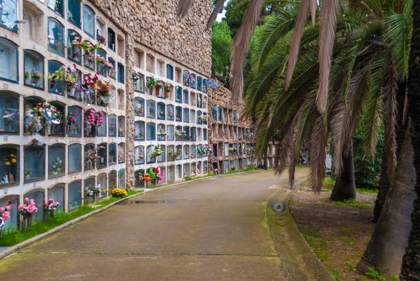Barcelona, Spain - November 17, 2018: Perspective view of the curved footpath with graves on the Montjuic Cemetery in overcast day