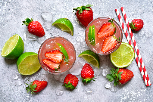 Homemade strawberry lemonade with lime in a glasses on a light grey slate, stone or concrete background. Top view with copy space.