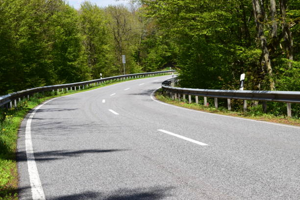 istock curvy country road in spring forest 1148844126