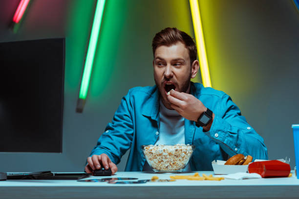 istock handsome and good-looking man holding computer mouse and eating popcorn 1148844181