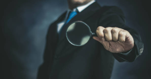 istock Businessman with Magnifying Glass on Dark Background 1148848127