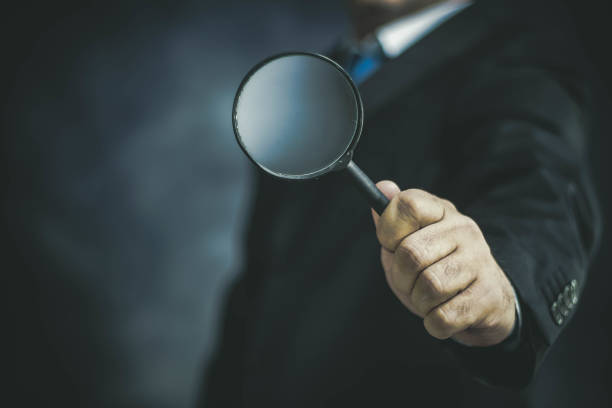 istock Businessman with Magnifying Glass on Dark Background 1148848201
